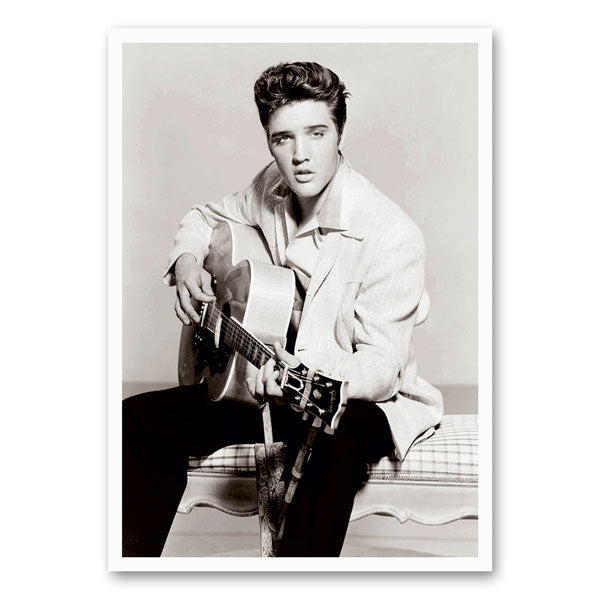Zwart-witfoto van Elvis Presley met een gitaar, in een iconische rock-‘n-roll houding.